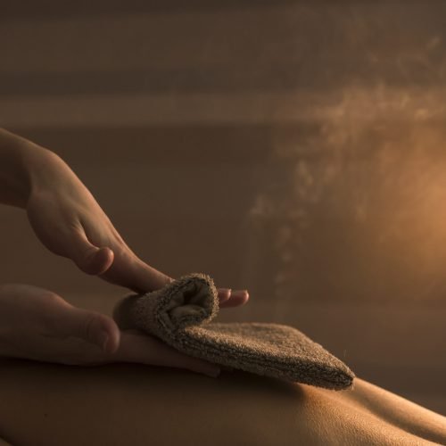 beautician-hand-massaging-woman-s-back-with-hot-towel-spa