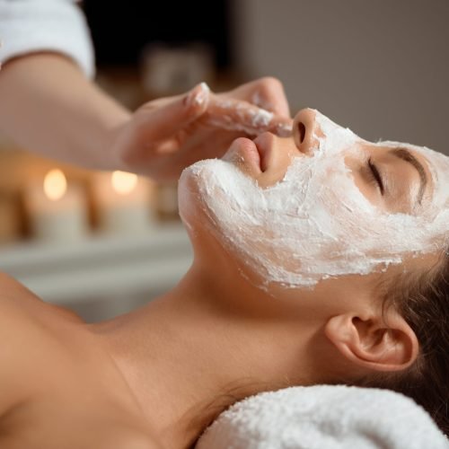 Young beautiful brunette girl in mask for face relaxing in spa salon. Eyes closed. Copy space.